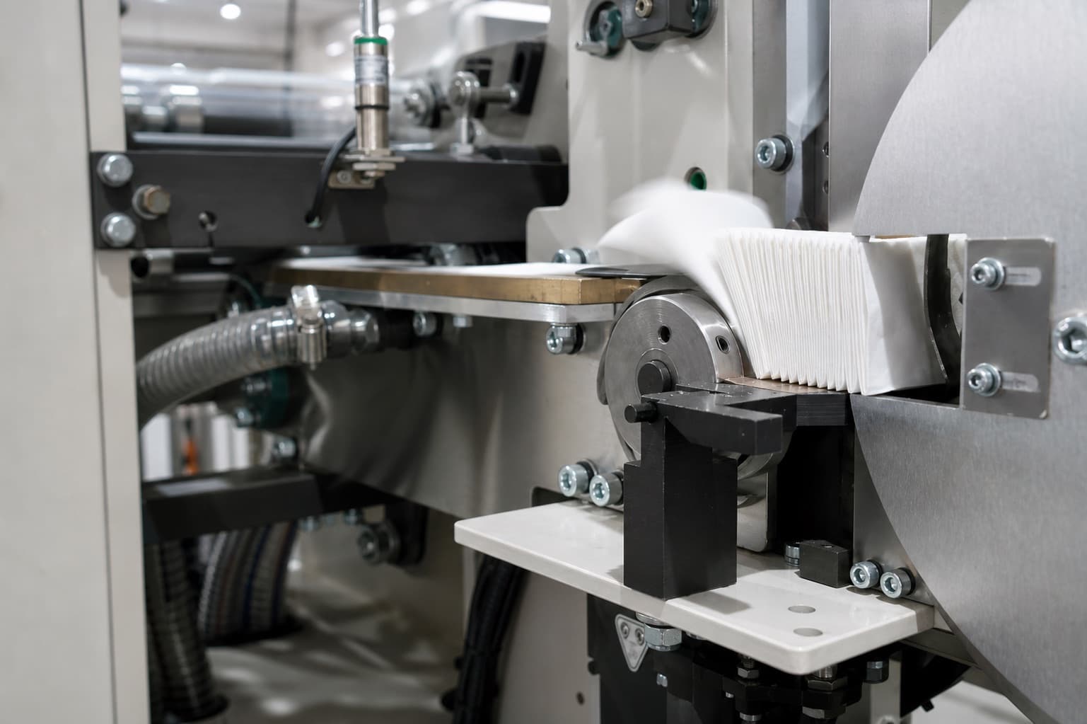 Folded pocket tissue exiting Jiufeng converting equipment in a process detail developed from factory footage